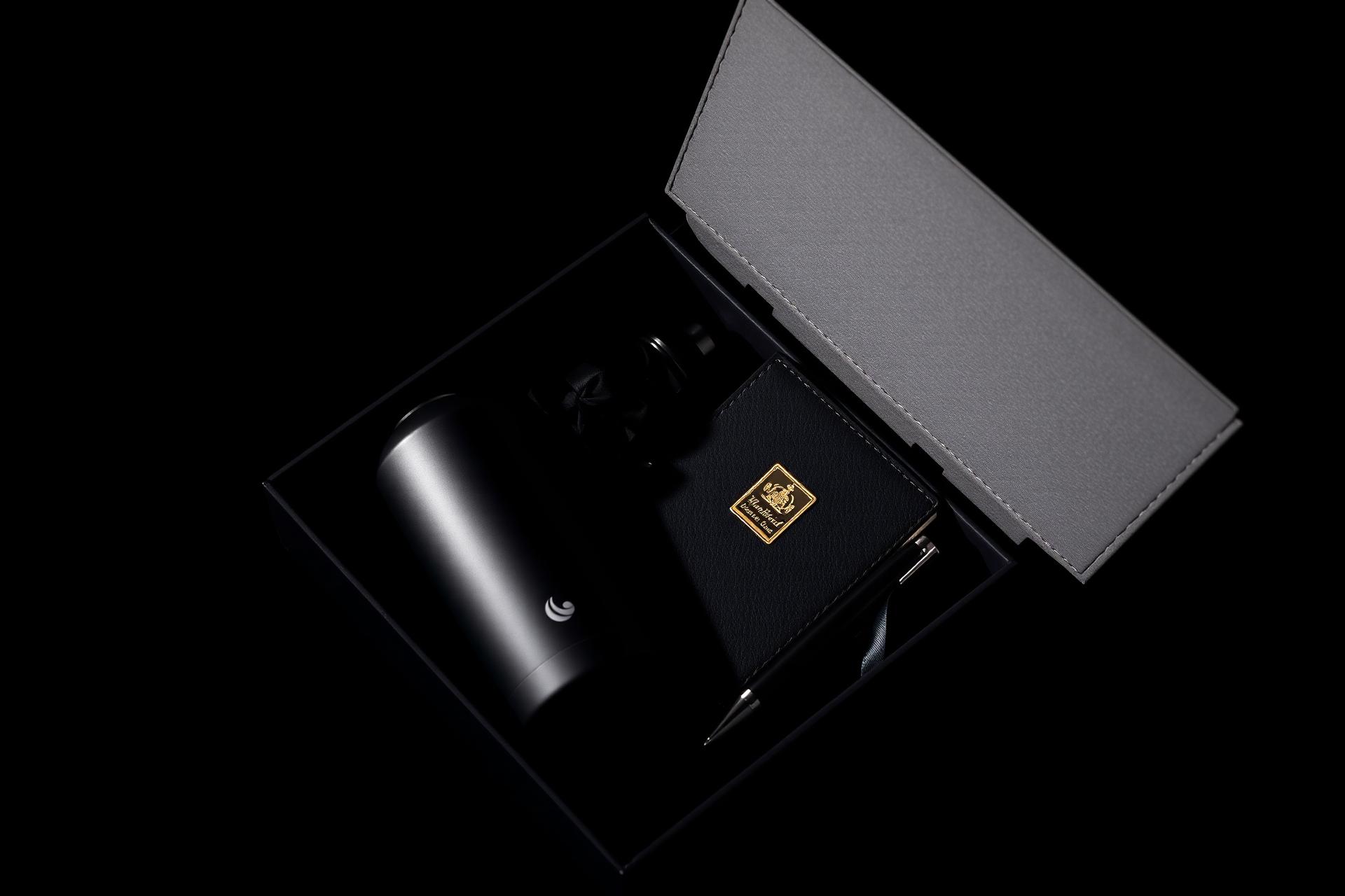 Kit corporativo premium preto com garrafa térmica fosca, caderno de couro e caneta, arranjados em caixa preta com fita de cetim